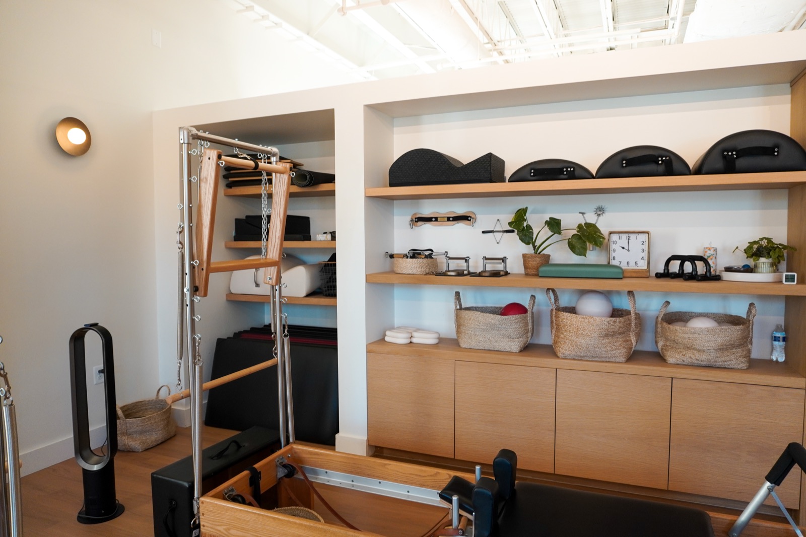 Barrels, rings, and Pilates apparatus arranged along the studio wall